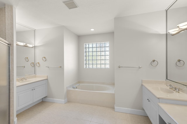 bathroom with a sink, a bath, two vanities, and visible vents