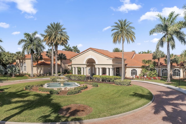 view of front facade featuring a front yard, stucco siding, and a tile roof