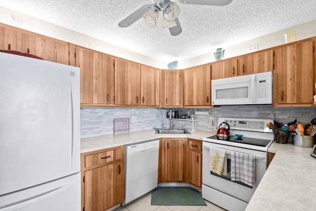 kitchen with white appliances, a ceiling fan, a sink, decorative backsplash, and light countertops