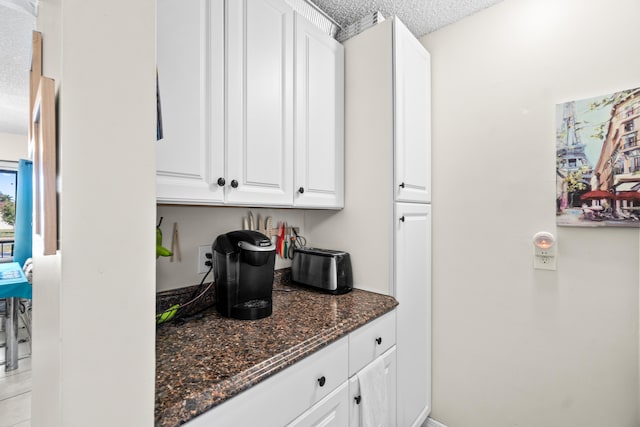 kitchen with white cabinetry, dark stone countertops, and a textured ceiling
