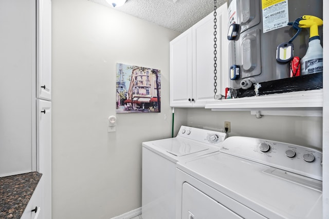 laundry area featuring baseboards, washer and clothes dryer, water heater, cabinet space, and a textured ceiling