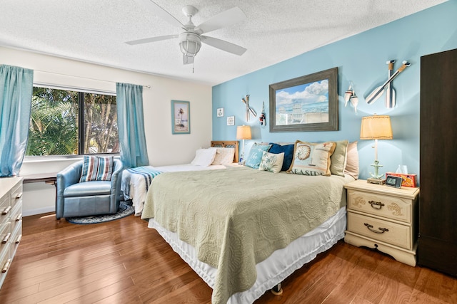 bedroom with ceiling fan, wood finished floors, and a textured ceiling