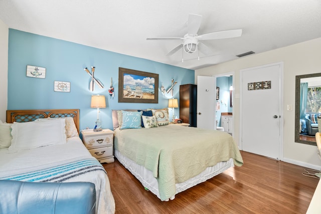 bedroom featuring a ceiling fan, wood finished floors, visible vents, and connected bathroom