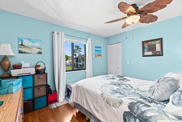 bedroom featuring ceiling fan, wood finished floors, a closet, and a textured ceiling