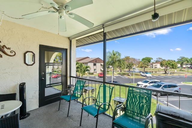 sunroom featuring a textured wall, a residential view, carpet floors, and ceiling fan