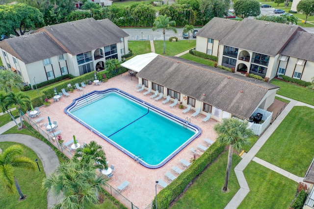 pool with a patio, a yard, and fence