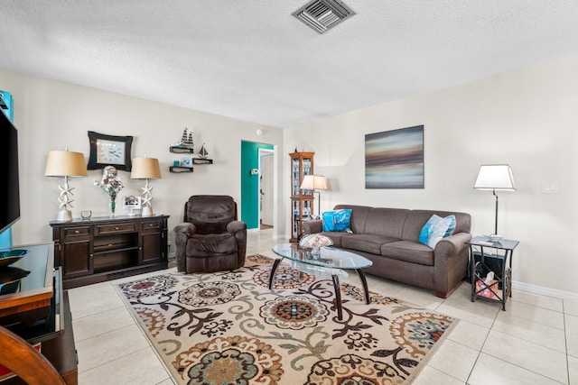 living area featuring light tile patterned floors, visible vents, baseboards, and a textured ceiling