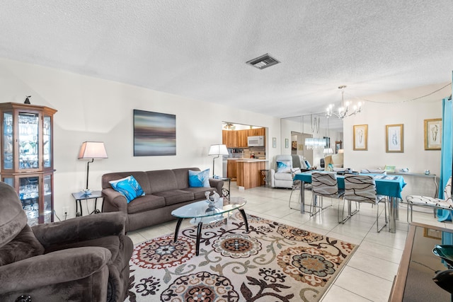 living area with a chandelier, visible vents, a textured ceiling, and light tile patterned floors