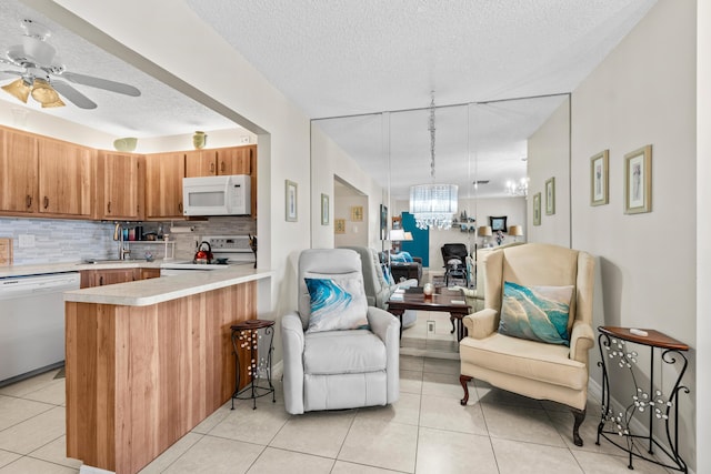 kitchen featuring a sink, backsplash, open floor plan, white appliances, and light countertops