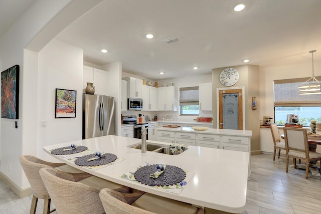 5561 1st Sq SW, Vero Beach, FL 32968 - kitchen with a spacious island, a sink, white cabinetry, stainless steel appliances, and visible vents