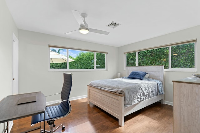 bedroom with visible vents, multiple windows, baseboards, and wood finished floors