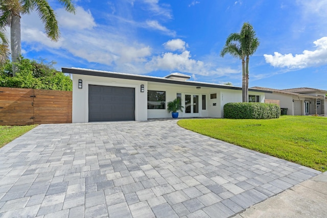single story home featuring fence, a front yard, stucco siding, decorative driveway, and an attached garage