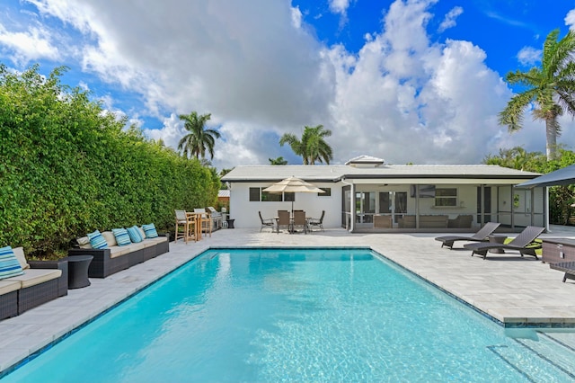 back of house with outdoor lounge area, a patio, outdoor dining area, and a fenced in pool