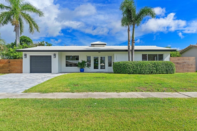 view of front of property with fence, a front yard, stucco siding, decorative driveway, and an attached garage