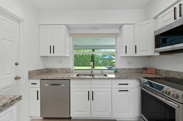 kitchen featuring a sink, light stone countertops, appliances with stainless steel finishes, and white cabinetry