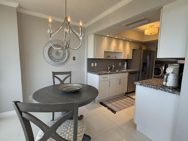 2003 N Ocean Blvd Unit 305N, Boca Raton, FL 33431 - kitchen with visible vents, crown molding, washer and dryer, white cabinetry, and stainless steel dishwasher