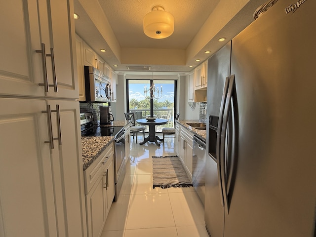 2003 N Ocean Blvd Unit 305N, Boca Raton, FL 33431 - kitchen featuring a tray ceiling, decorative backsplash, appliances with stainless steel finishes, light tile patterned flooring, and white cabinetry
