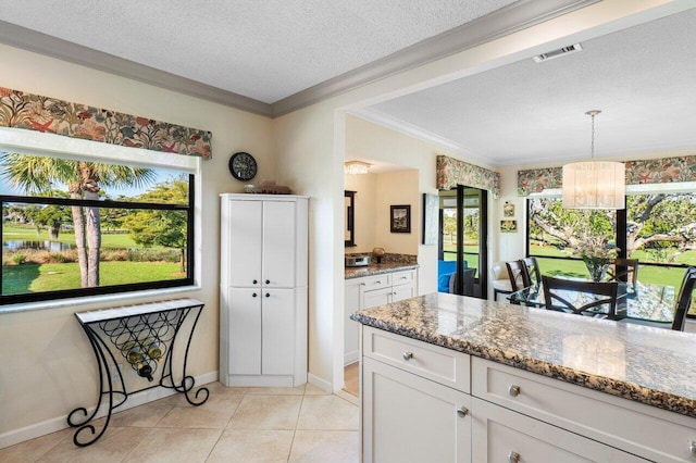 kitchen with visible vents, light stone counters, a textured ceiling, white cabinetry, and an inviting chandelier