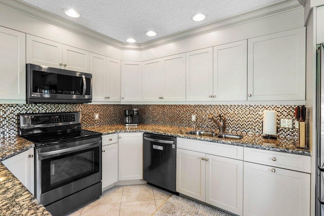 kitchen with a sink, appliances with stainless steel finishes, dark stone countertops, and light tile patterned floors