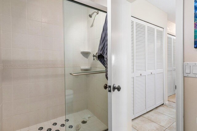 full bath with tile patterned flooring, a stall shower, and a closet