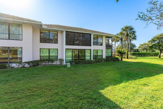 rear view of house with stucco siding and a lawn
