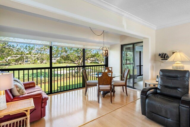 interior space featuring crown molding, a notable chandelier, light wood-type flooring, and a textured ceiling