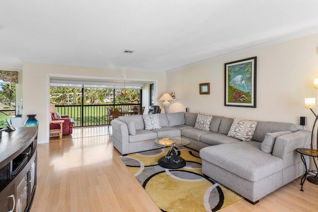 living area with visible vents, light wood-style flooring, and ornamental molding