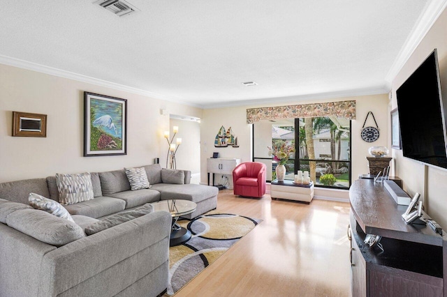 living room featuring light wood-style flooring, visible vents, and ornamental molding
