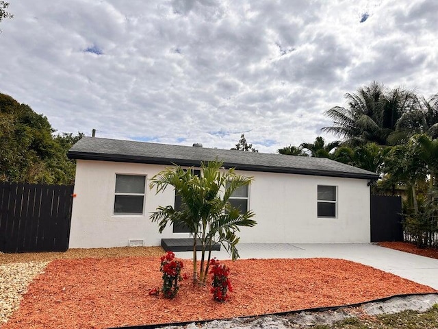 view of front facade featuring concrete driveway, fence, and stucco siding