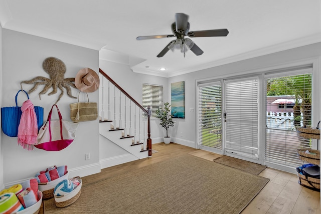 entrance foyer with ornamental molding, baseboards, ceiling fan, and wood finished floors