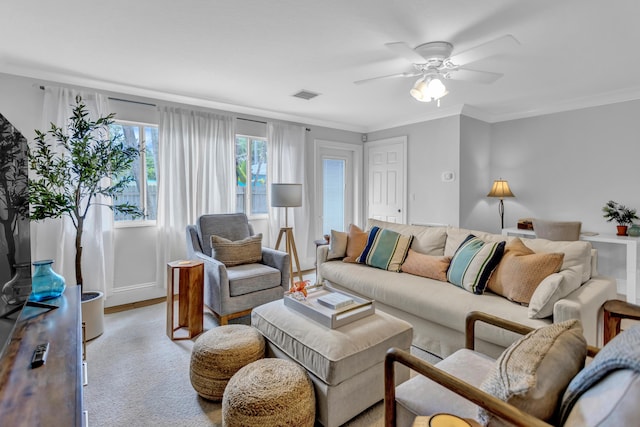 living area with ornamental molding, baseboards, ceiling fan, and visible vents