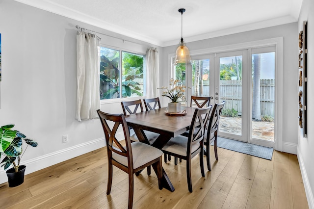 dining space featuring light wood finished floors, baseboards, crown molding, and french doors