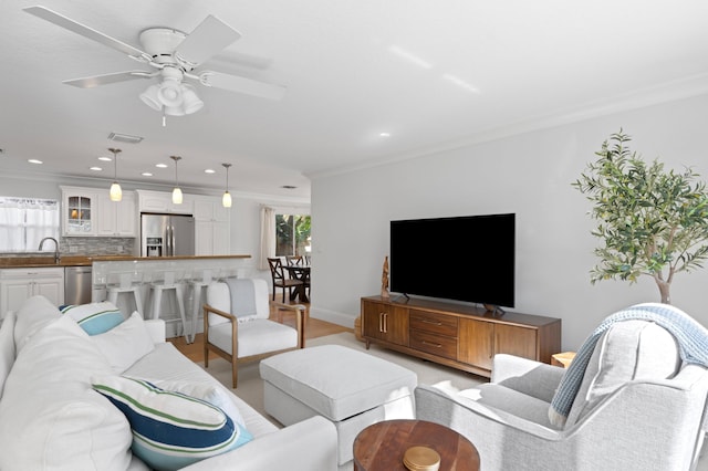 living area with visible vents, ceiling fan, and ornamental molding
