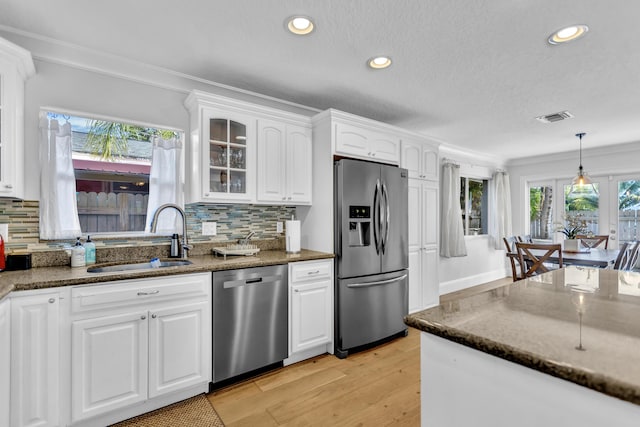 kitchen featuring dark stone counters, a sink, visible vents, white cabinets, and appliances with stainless steel finishes