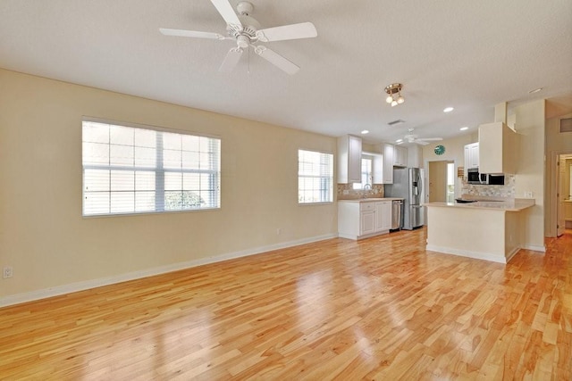 kitchen featuring stainless steel appliances, ceiling fan, open floor plan, light wood-type flooring, and recessed lighting