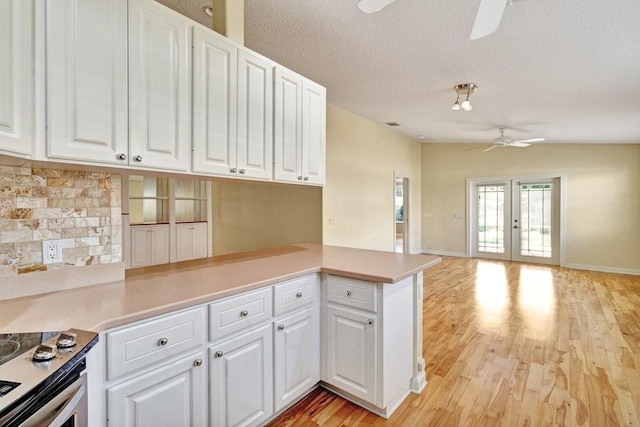 kitchen featuring a ceiling fan, light wood-style floors, backsplash, white cabinetry, and a textured ceiling