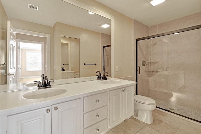 full bathroom featuring a stall shower, toilet, double vanity, and tile patterned floors