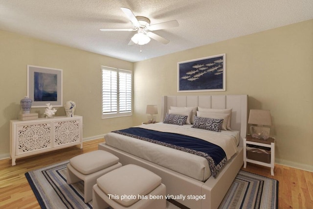 bedroom with wood finished floors, a textured ceiling, baseboards, and ceiling fan
