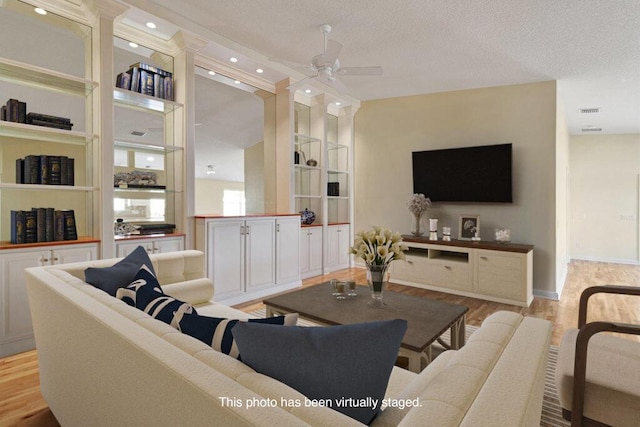 living room featuring wood finished floors, a ceiling fan, baseboards, recessed lighting, and a textured ceiling