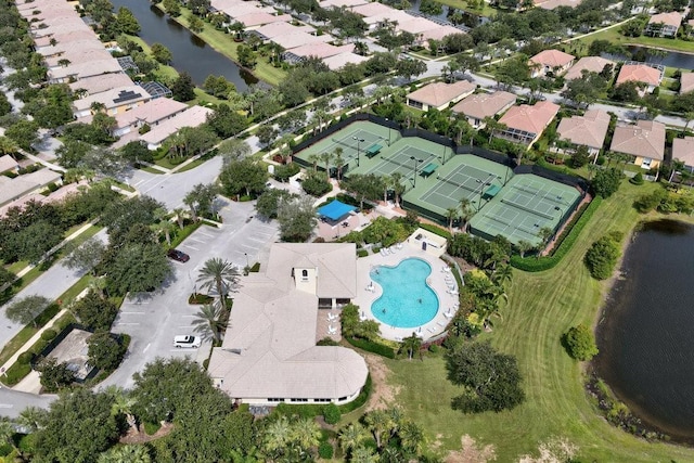 aerial view of property's location featuring a pool, a nearby body of water, and nearby suburban area