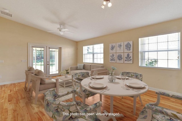 dining room featuring light wood-type flooring, a ceiling fan, healthy amount of natural light, vaulted ceiling, and baseboards