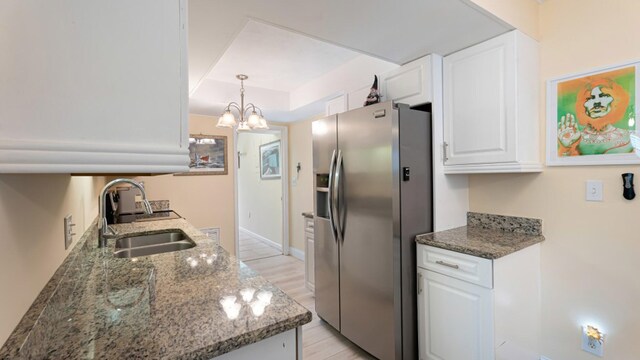 4142 NE Robin Ct, Jensen Beach, FL 34957 - kitchen with stainless steel fridge with ice dispenser, white cabinets, a chandelier, and dark stone counters