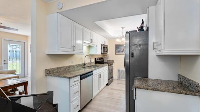 4142 NE Robin Ct, Jensen Beach, FL 34957 - kitchen with appliances with stainless steel finishes, white cabinetry, dark stone countertops, and light wood-style flooring