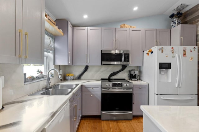 kitchen featuring visible vents, a sink, stainless steel appliances, vaulted ceiling, and light countertops