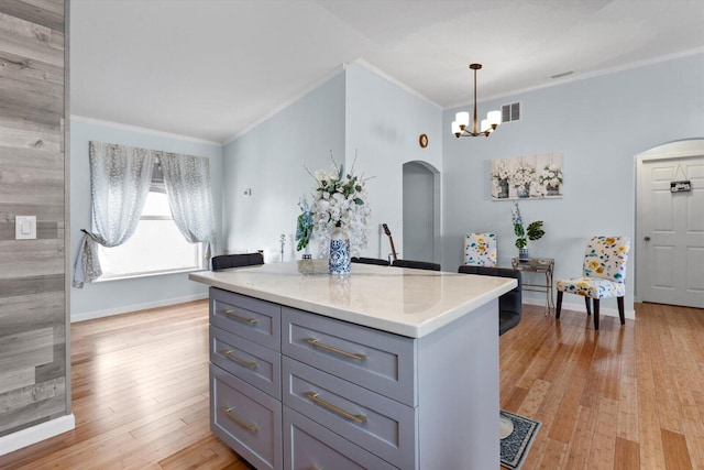 kitchen with arched walkways, light wood finished floors, gray cabinetry, and light countertops