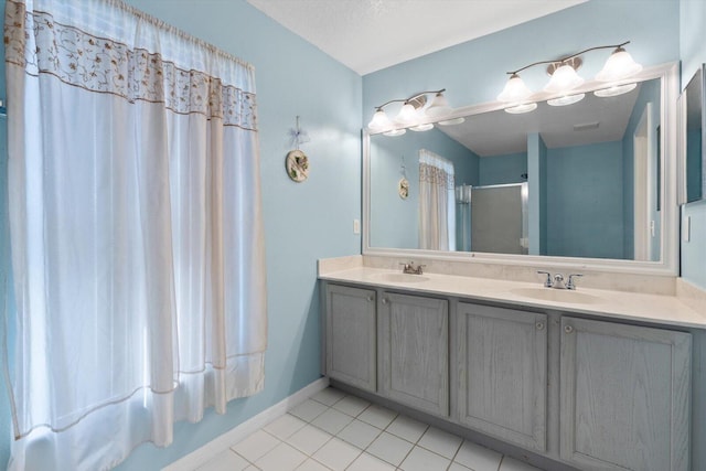 bathroom with a sink, a shower with door, double vanity, and tile patterned flooring