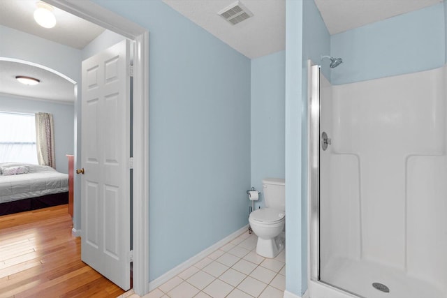 ensuite bathroom with visible vents, baseboards, toilet, a stall shower, and ensuite bathroom