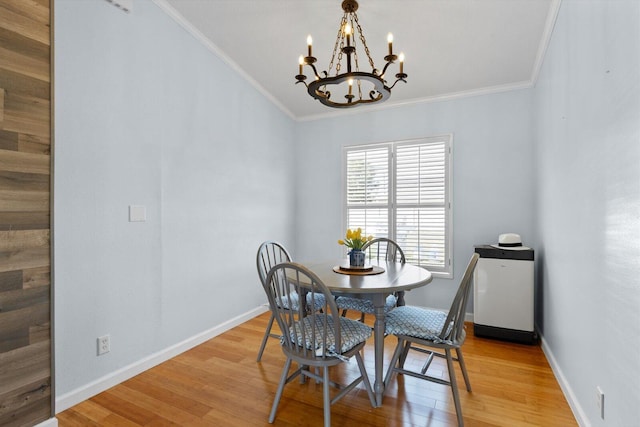 dining area featuring crown molding, a notable chandelier, baseboards, and light wood-type flooring