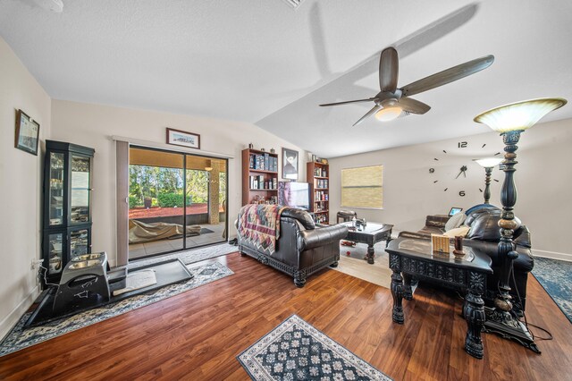 living area featuring vaulted ceiling, wood finished floors, baseboards, and ceiling fan