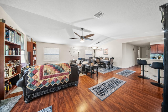 living area with visible vents, a ceiling fan, a textured ceiling, wood finished floors, and lofted ceiling